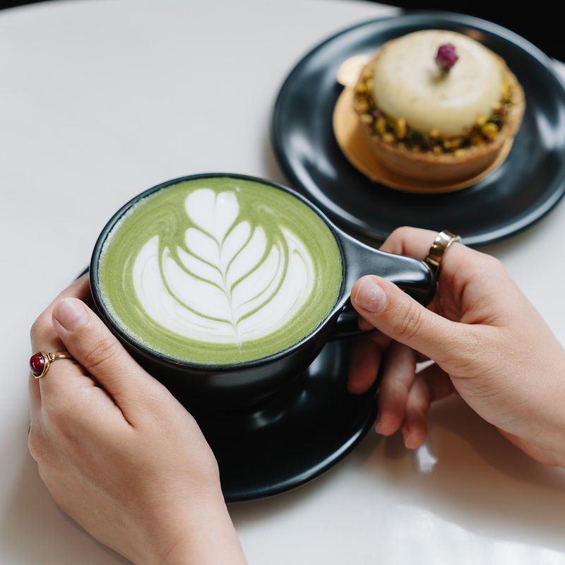 Hands holding a matcha latte at Momento Café
