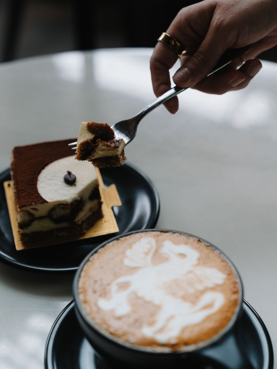 A slice of tiramisu beside a latte at Momento Café