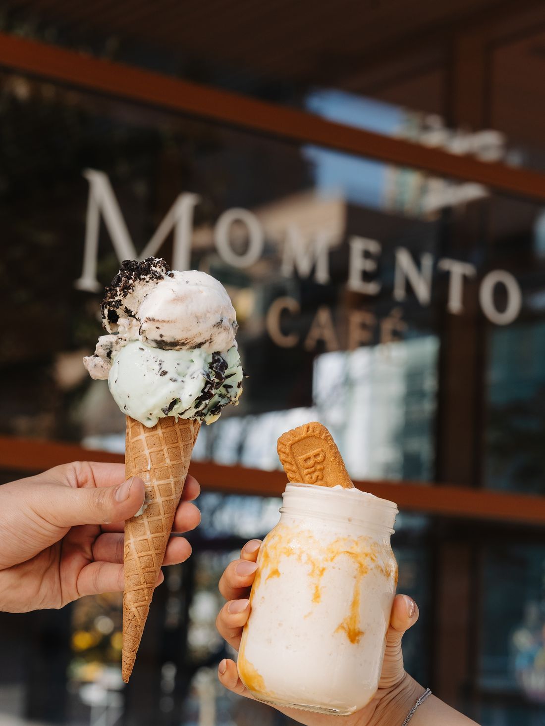 Gelato cone and milkshake held up in front of the Momento Café sign