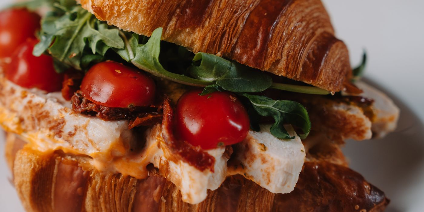 A croissant sandwich with tomato and arugula